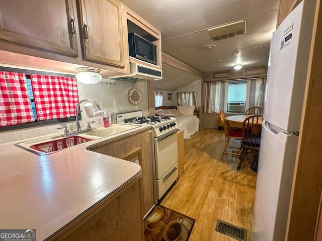 kitchen featuring visible vents, light wood-style flooring, white appliances, and a sink