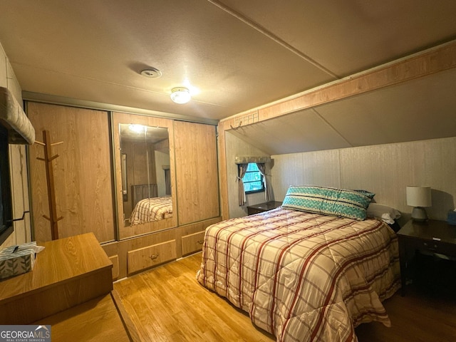 bedroom featuring a closet, wooden walls, and wood finished floors