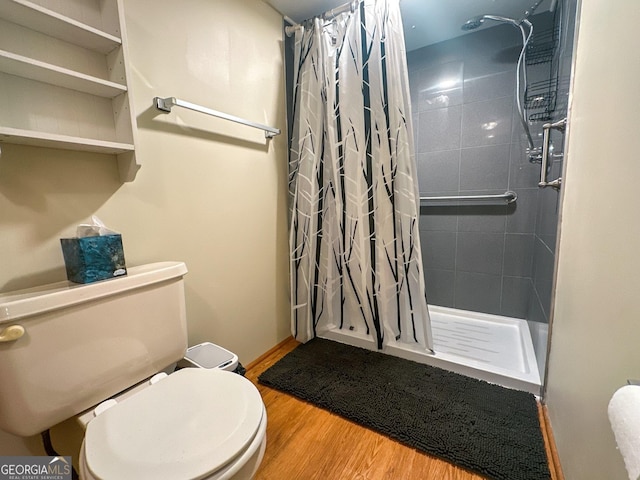 full bath with a stall shower, toilet, baseboards, and wood finished floors