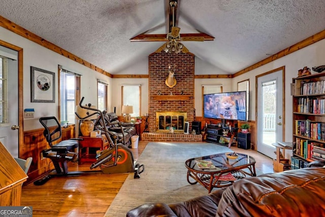 living area with a healthy amount of sunlight, a brick fireplace, a textured ceiling, and vaulted ceiling