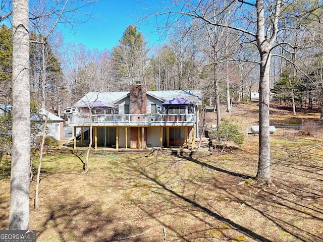 back of property with a wooden deck, a chimney, and stairs