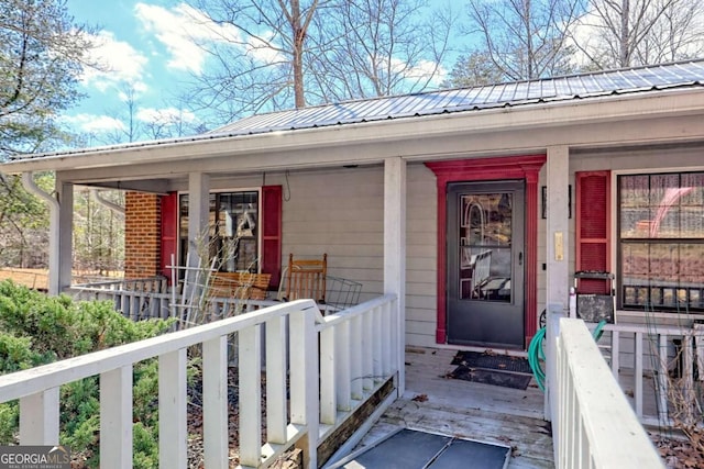 doorway to property featuring a porch and metal roof