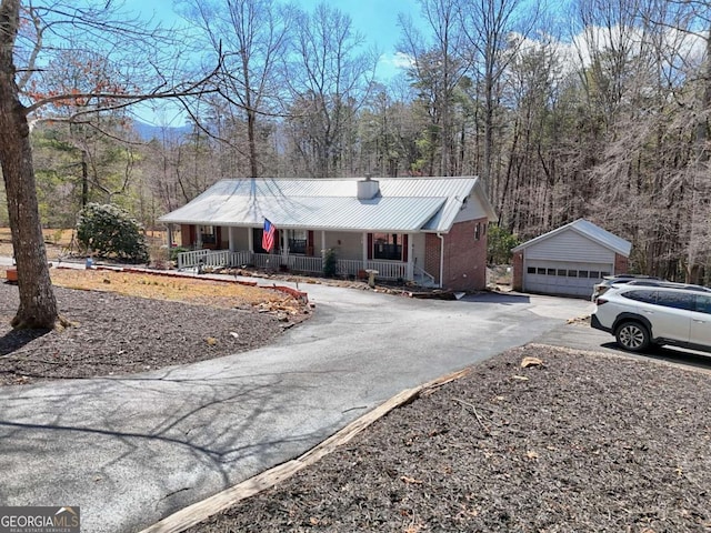 single story home featuring a detached garage, covered porch, an outdoor structure, metal roof, and brick siding