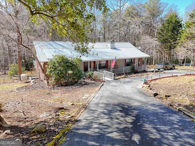 view of front of house with metal roof, covered porch, and aphalt driveway