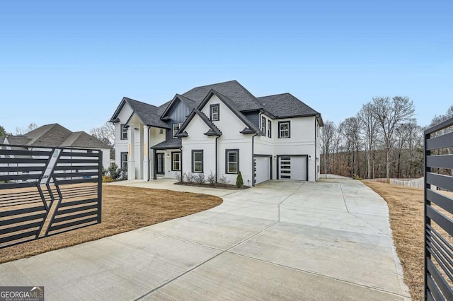 french provincial home with an attached garage, a shingled roof, driveway, and fence