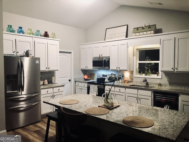 kitchen with dark wood-style flooring, a sink, appliances with stainless steel finishes, white cabinetry, and a kitchen breakfast bar