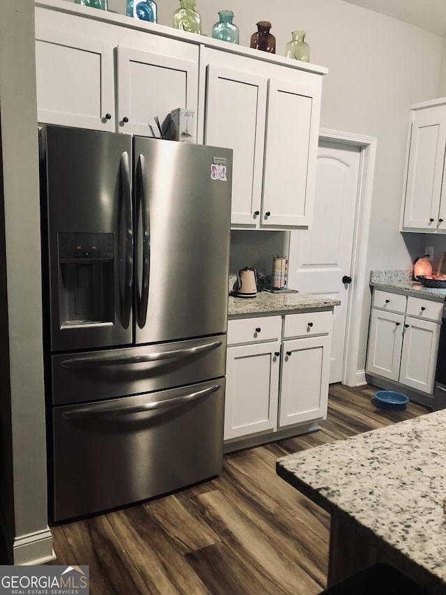 kitchen with light stone counters, dark wood-style flooring, stainless steel refrigerator with ice dispenser, and white cabinetry