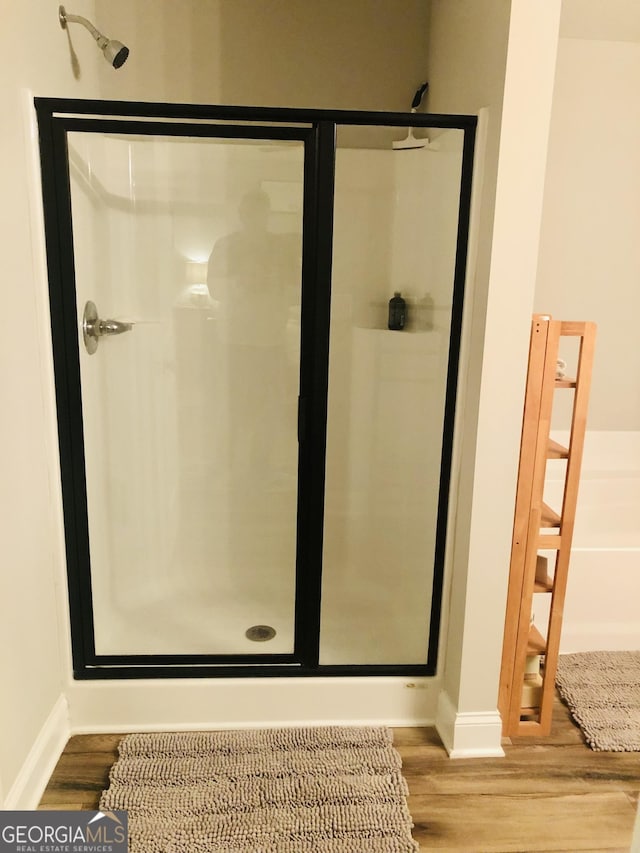 bathroom featuring a shower stall, wood finished floors, and baseboards