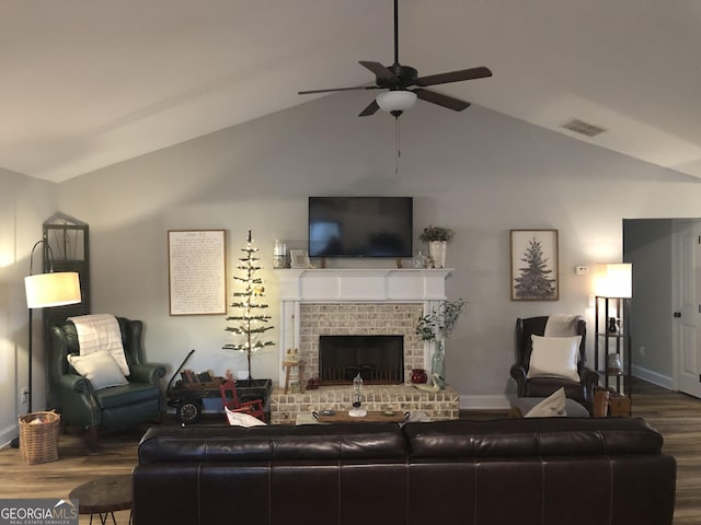 living room with visible vents, ceiling fan, vaulted ceiling, a fireplace, and wood finished floors