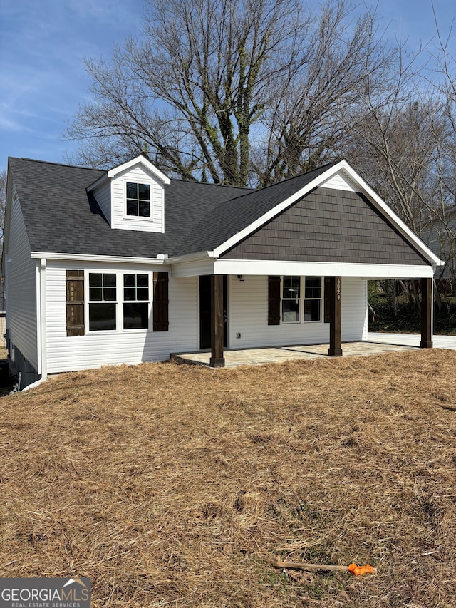 view of front of home featuring an attached carport, a front yard, and roof with shingles