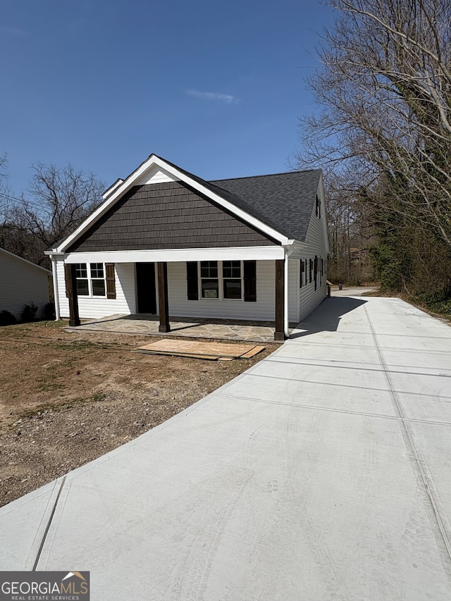 view of front facade with concrete driveway and a shingled roof