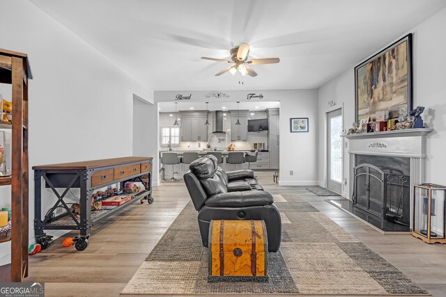 living area featuring a wealth of natural light, light wood-style floors, and ceiling fan