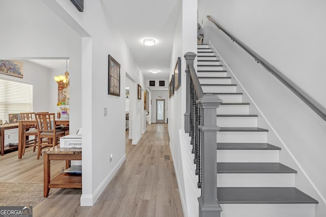 stairway with a chandelier, baseboards, and wood finished floors