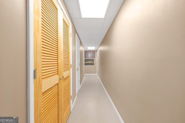 hallway with a drop ceiling and baseboards