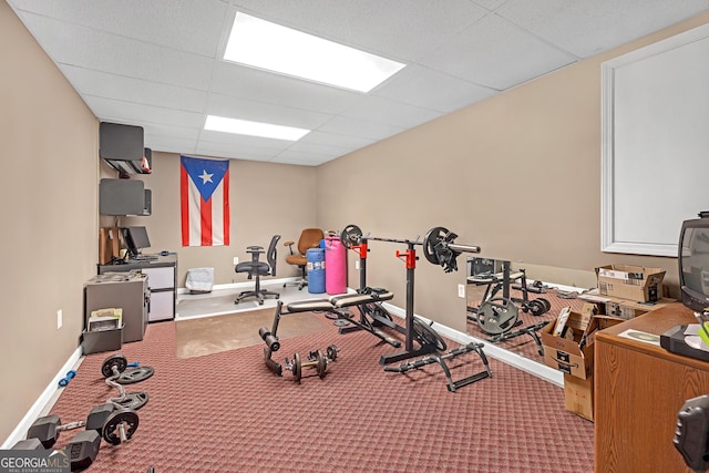 exercise room featuring a drop ceiling, baseboards, and carpet floors