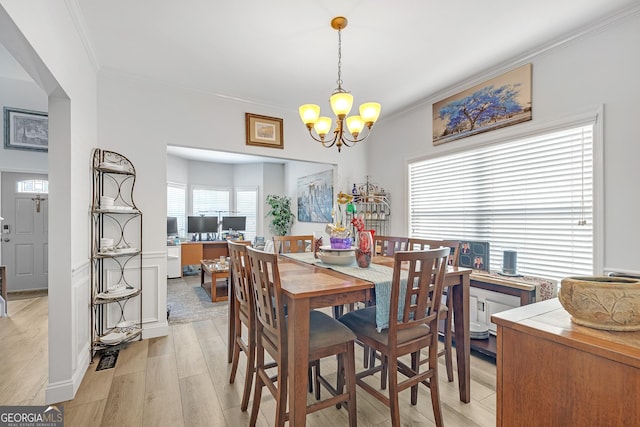 dining space with light wood-style flooring, an inviting chandelier, and ornamental molding