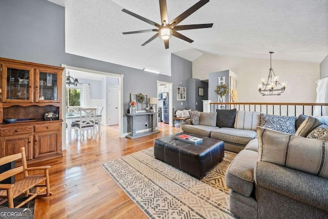 living area featuring light wood-type flooring, a textured ceiling, high vaulted ceiling, and ceiling fan with notable chandelier