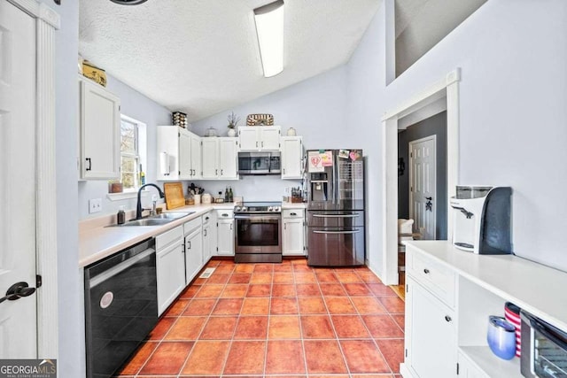 kitchen featuring lofted ceiling, a sink, light countertops, white cabinets, and appliances with stainless steel finishes