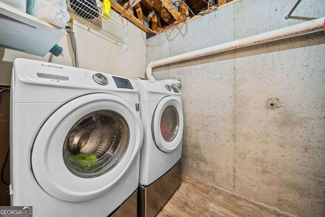 clothes washing area with washer and dryer and wood finished floors