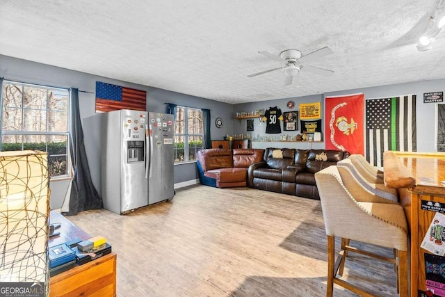 living room featuring a textured ceiling, ceiling fan, and wood finished floors