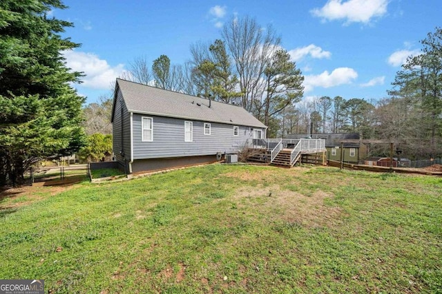 rear view of house with fence, a yard, a wooden deck, central AC unit, and stairs