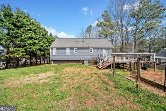 rear view of house with a yard, a deck, stairs, and fence