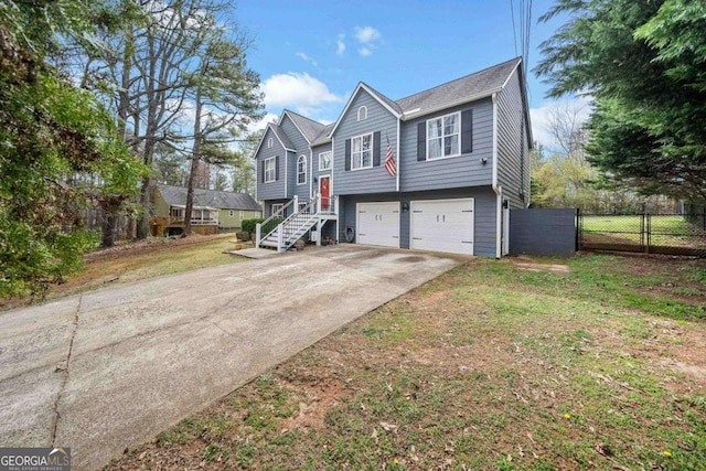 raised ranch with a garage, driveway, and fence