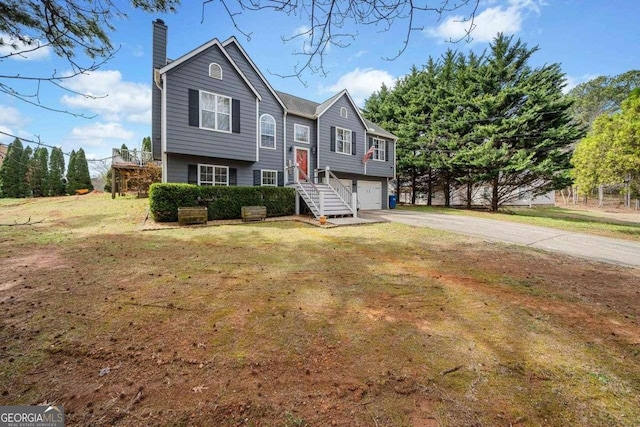 bi-level home with a garage, a front lawn, a chimney, and driveway