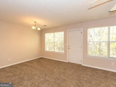 unfurnished room with an inviting chandelier, baseboards, and carpet floors