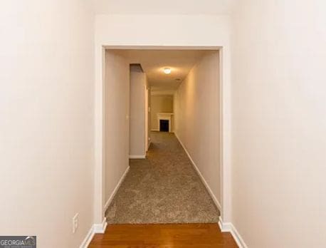 corridor with baseboards and wood finished floors