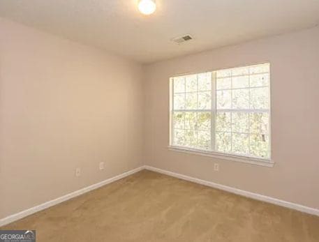 spare room with visible vents, carpet, and baseboards