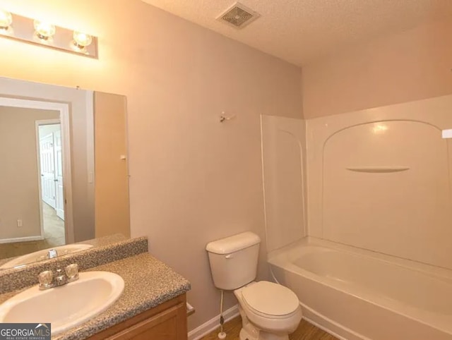 bathroom with visible vents, tub / shower combination, toilet, vanity, and a textured ceiling