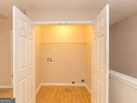 laundry area with laundry area, hookup for a washing machine, baseboards, and wood finished floors