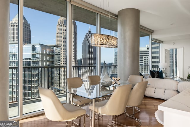 dining area with expansive windows, a city view, and wood finished floors