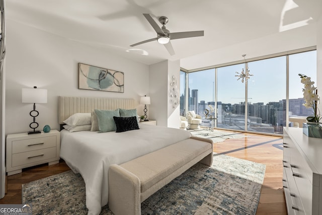 bedroom with a ceiling fan, access to outside, a view of city, and wood finished floors