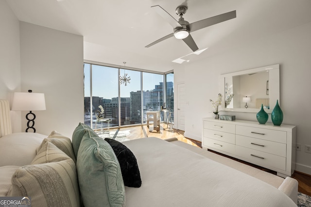 bedroom featuring a city view, floor to ceiling windows, wood finished floors, a ceiling fan, and access to outside