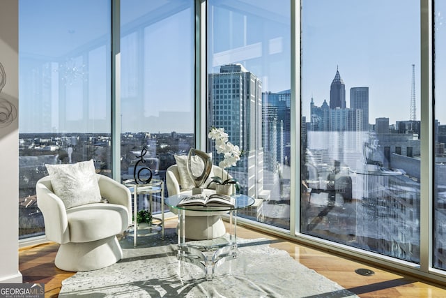 living area with a view of city, wood finished floors, and floor to ceiling windows