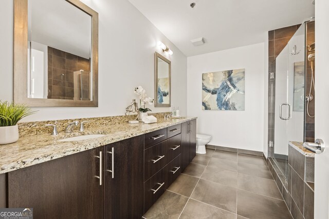 full bath featuring double vanity, a sink, a shower stall, tile patterned floors, and toilet