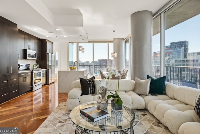 living room featuring a city view, recessed lighting, a wall of windows, and light wood-style floors