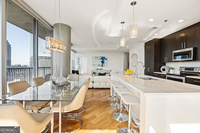 kitchen with a kitchen bar, visible vents, light wood-style flooring, a sink, and appliances with stainless steel finishes