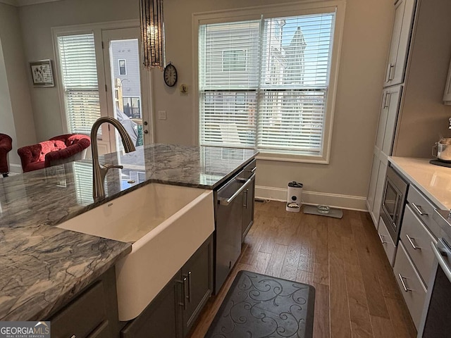 kitchen featuring stainless steel dishwasher, plenty of natural light, dark wood-style floors, and a sink