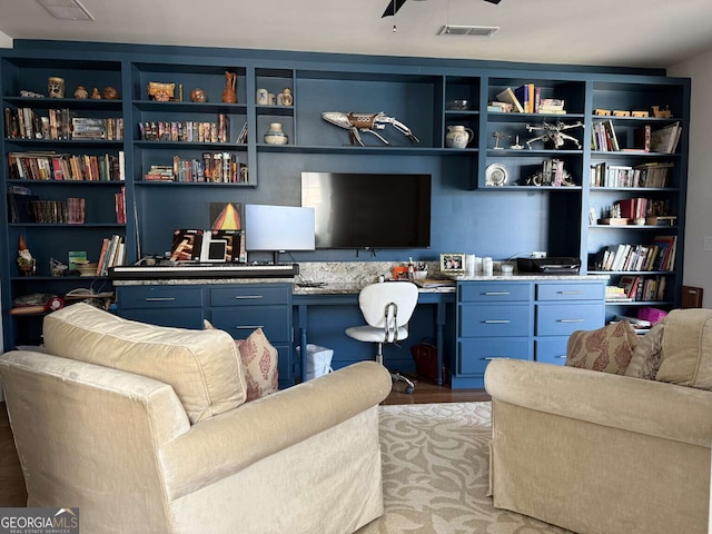 interior space featuring light wood-style floors, visible vents, built in desk, and ceiling fan