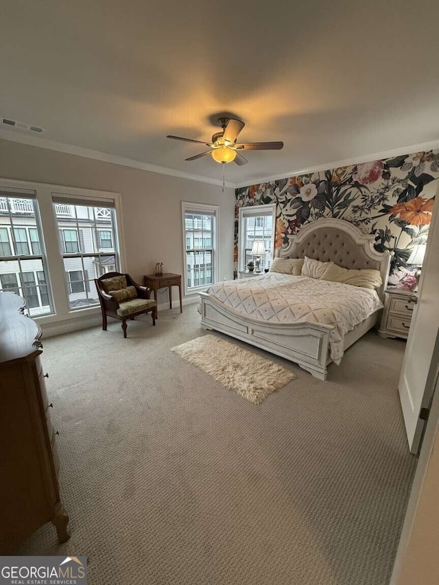 bedroom with visible vents, light colored carpet, crown molding, and ceiling fan