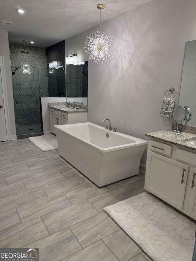 bathroom with visible vents, two vanities, a sink, a shower stall, and a freestanding bath