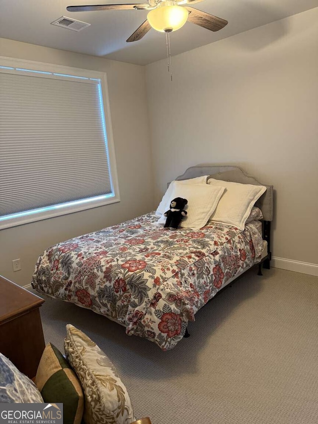 carpeted bedroom with visible vents, baseboards, and a ceiling fan