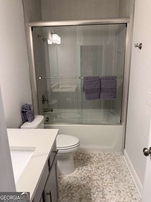 full bathroom featuring vanity, toilet, baseboards, and bath / shower combo with glass door