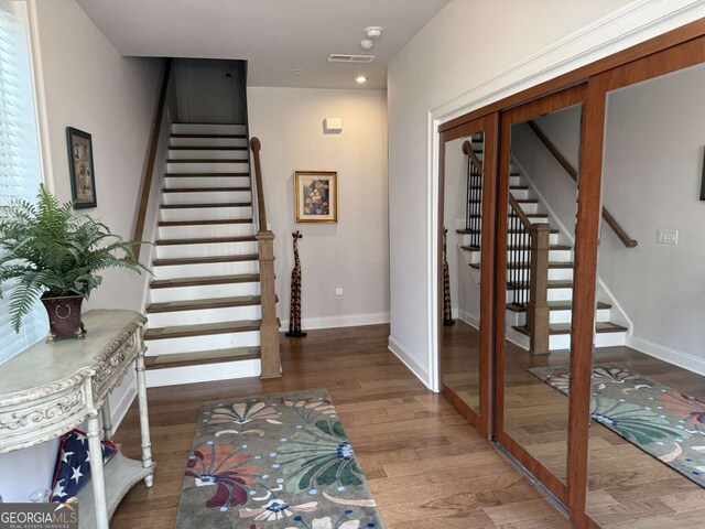 foyer featuring stairs, visible vents, wood finished floors, and baseboards