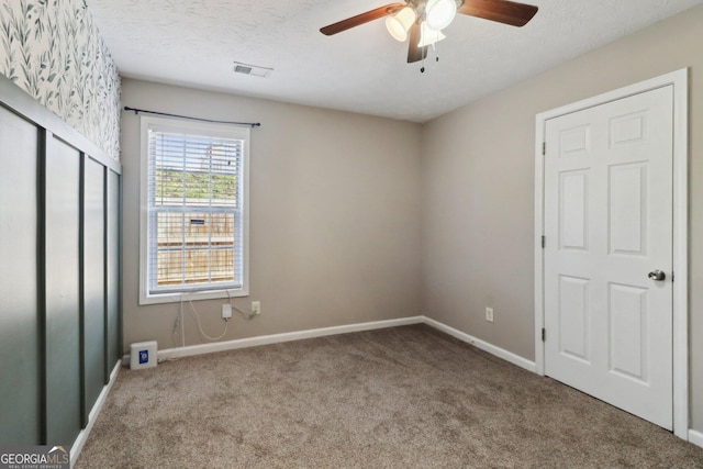 unfurnished bedroom featuring visible vents, a ceiling fan, a textured ceiling, carpet floors, and baseboards