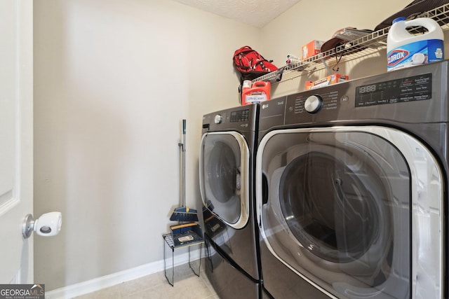 clothes washing area featuring baseboards, washer and clothes dryer, laundry area, tile patterned floors, and a textured ceiling