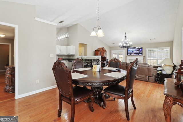 dining space with lofted ceiling, light wood-style flooring, a notable chandelier, and baseboards